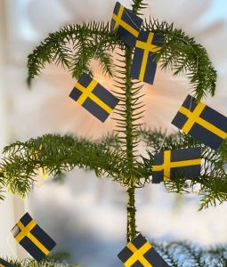 Girlang med 20 små svenska flaggor hängandes i en julgran